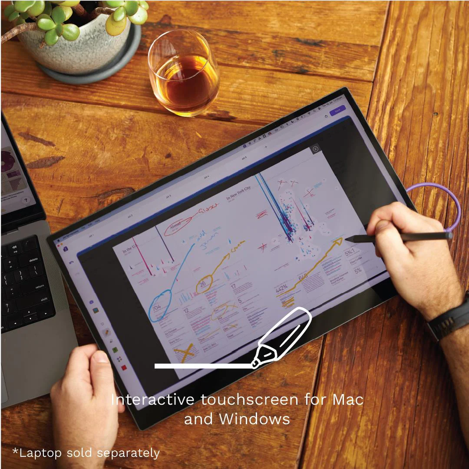 Een man gebruikt een stylus op een touchscreen monitor. Een laptop staat ernaast.