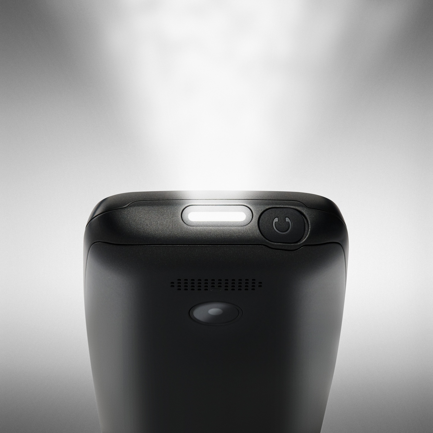 Primo piano della parte superiore di un telefono nero con luce LED accesa e barra della fotocamera.