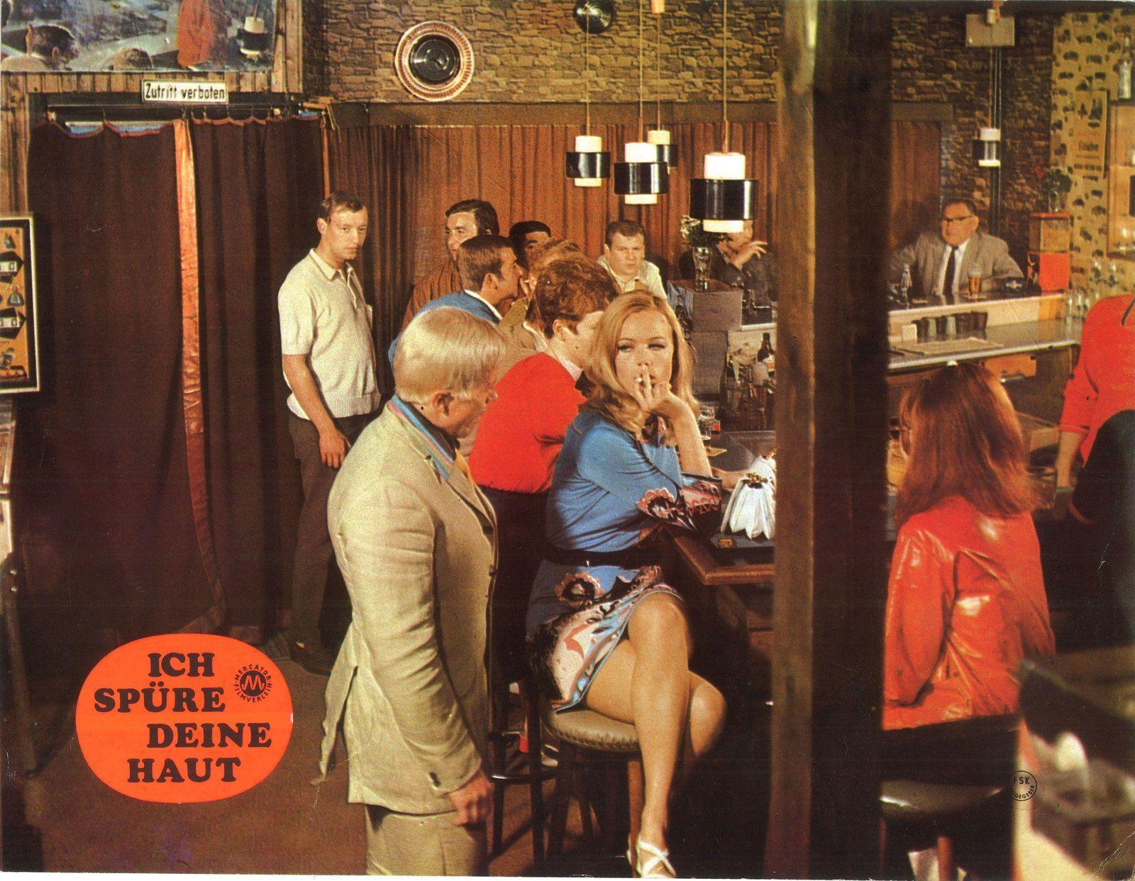 Frauen rauchen in einer Bar. Ein Mann im Anzug sitzt am Tresen.