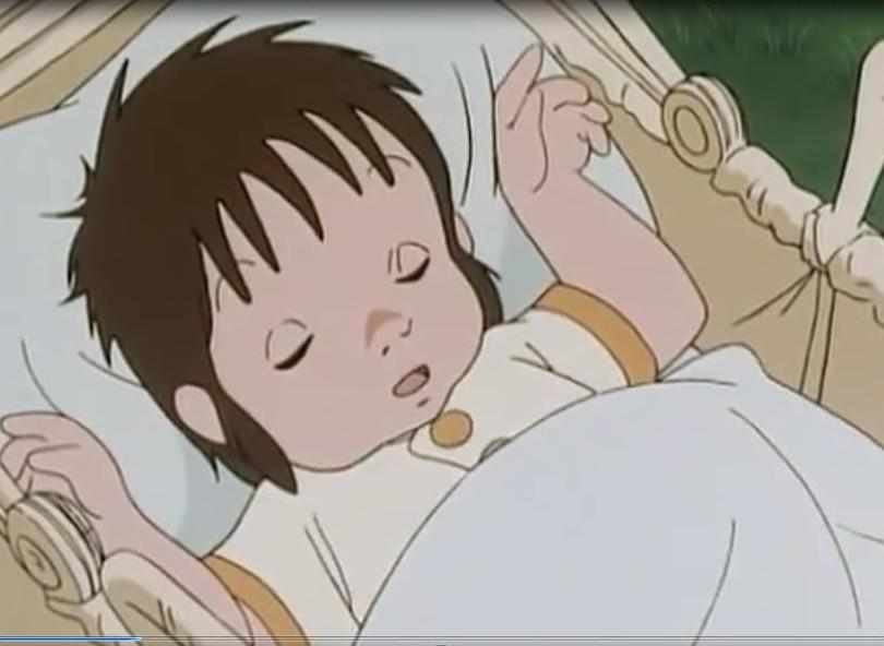 Ein Baby schläft in einer Wiege, mit braunen Haaren und einem gelben Kragen.