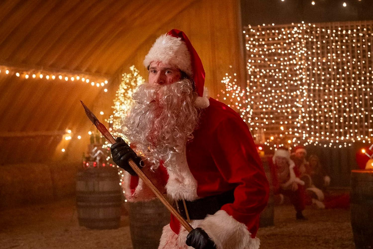 Ein blutbefleckter Weihnachtsmann mit Bart hält eine Waffe in einem Raum mit Lichterketten.