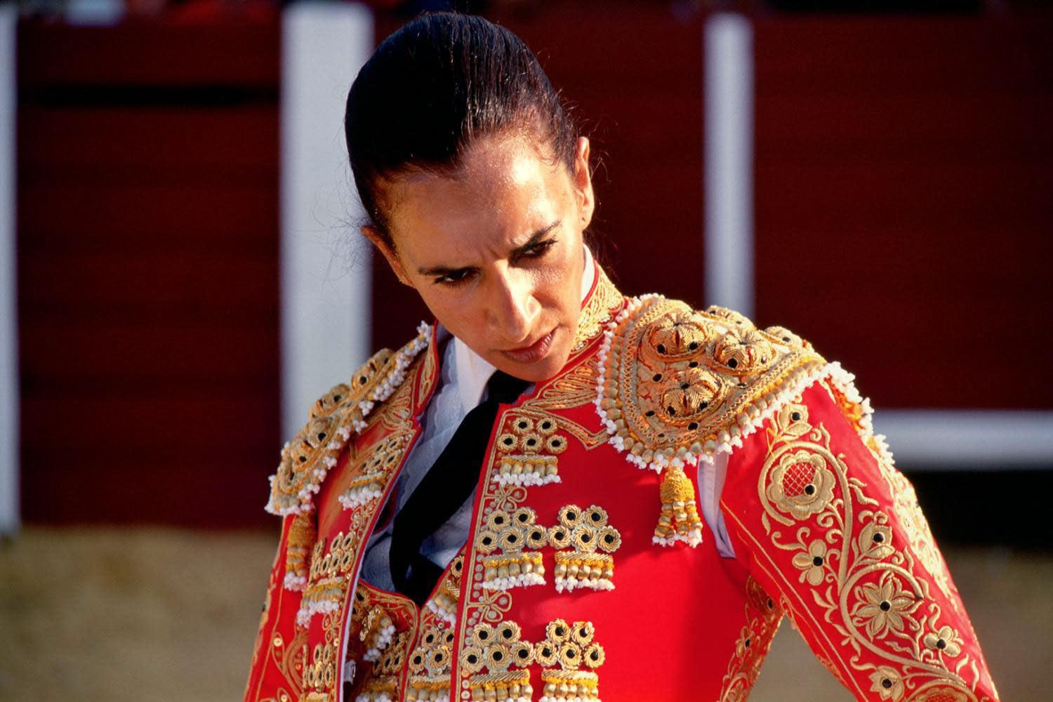Ein Matador in einem roten, gold bestickten Anzug blickt nach unten.