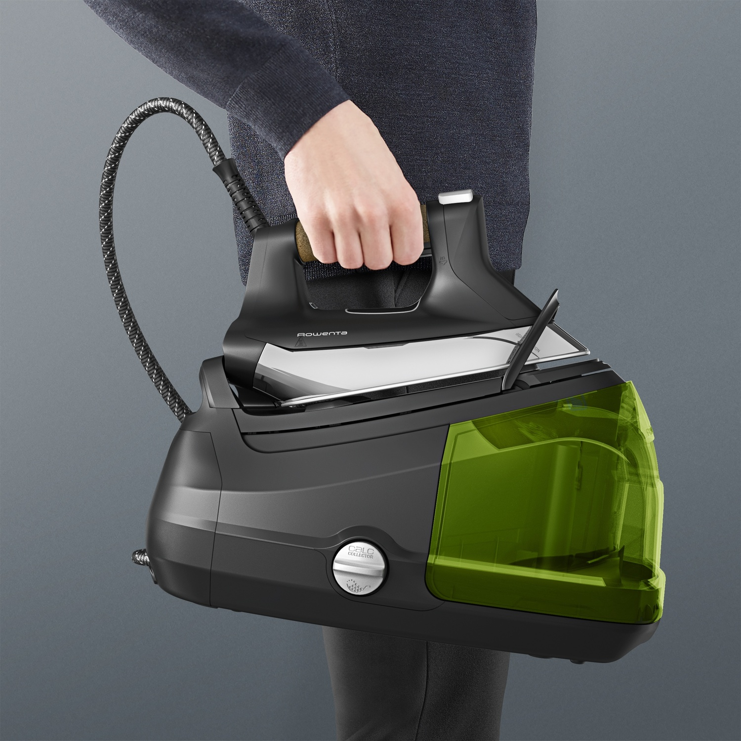 Una persona tiene un ferro da stiro a vapore nero con serbatoio dell'acqua verde.