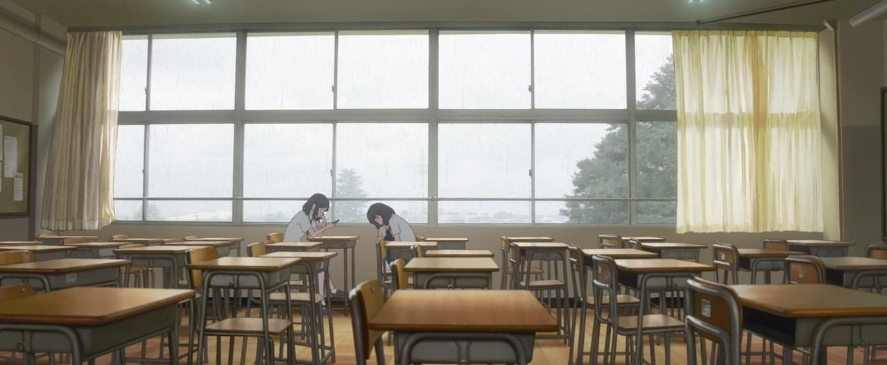Klassenzimmer mit vielen Schreibtischen und zwei Mädchen vor einem großen Fenster.