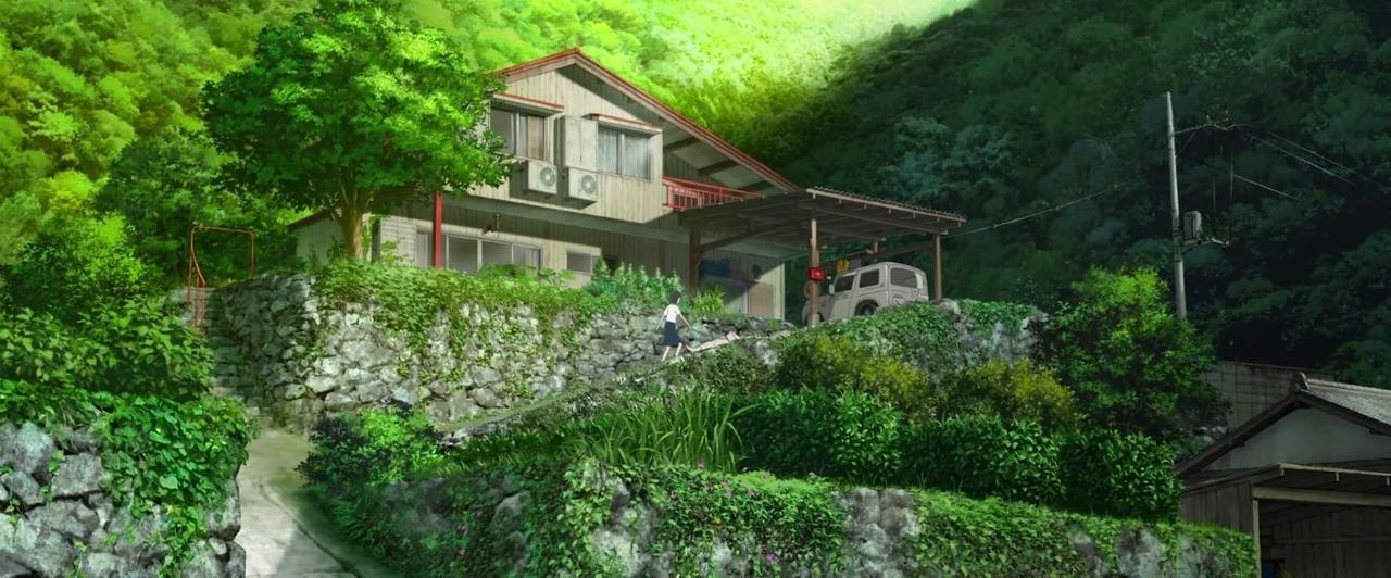 Ein Haus auf einem Hügel mit üppiger Vegetation. Eine Person geht die Straße entlang.