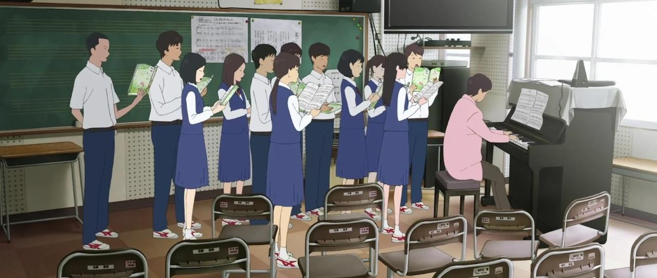 Schüler singen im Chor vor einem Klavier und einer Tafel in einem Klassenzimmer.