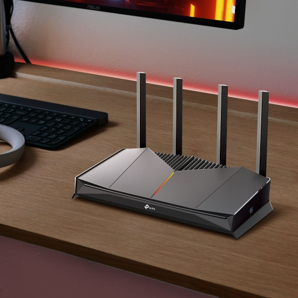 Egy fekete TP-Link Wi-Fi router négy antennával faasztalon áll.