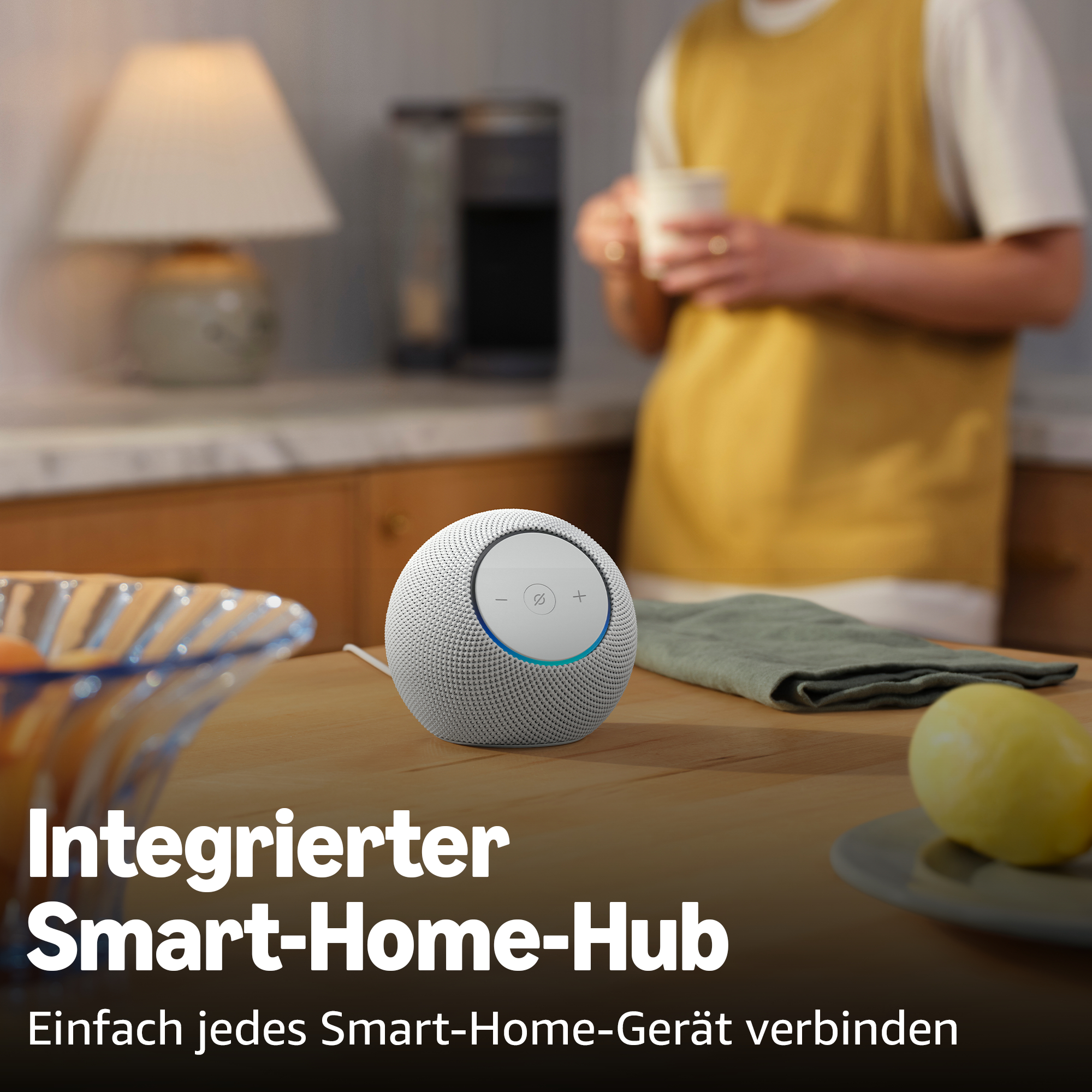 Ein weißer smarter Lautsprecher auf einem Holztisch, daneben eine Zitrone.