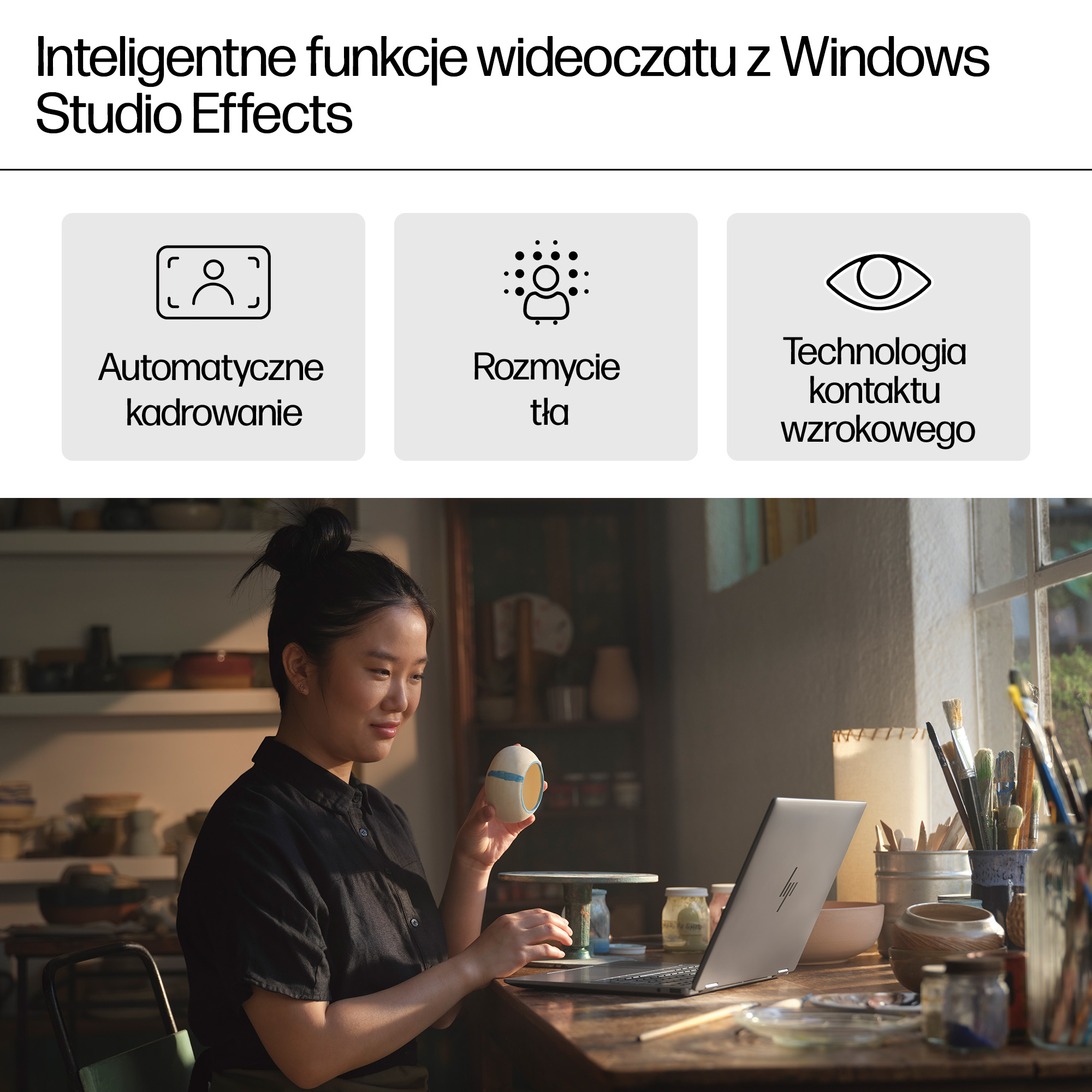 Kobieta trzyma kubek, pracując na laptopie w pracowni z materiałami artystycznymi.