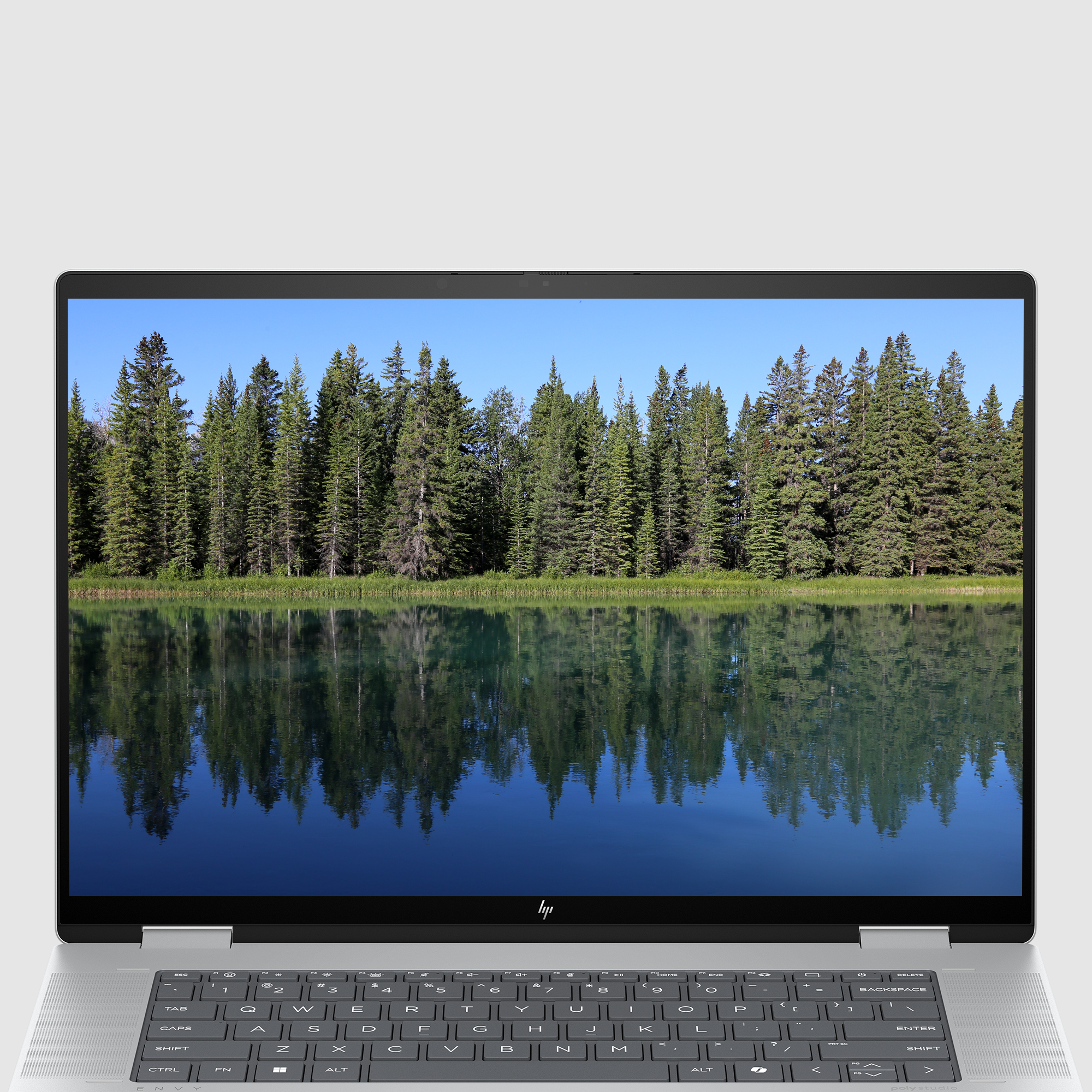 Laptop wyświetla odbicie drzew i nieba w spokojnym jeziorze.