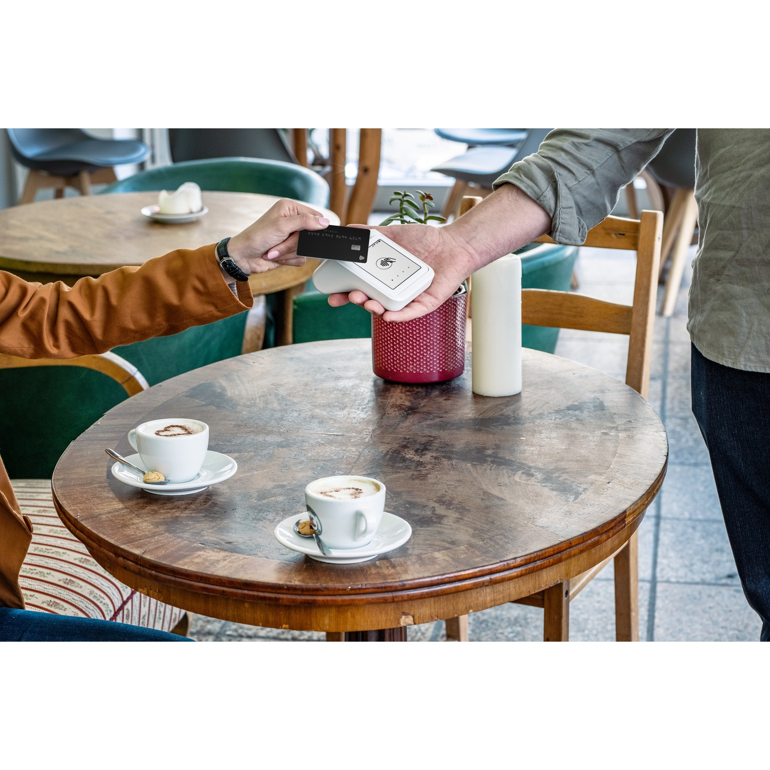 Una persona paga con carta di credito a un tavolo con due caffè.