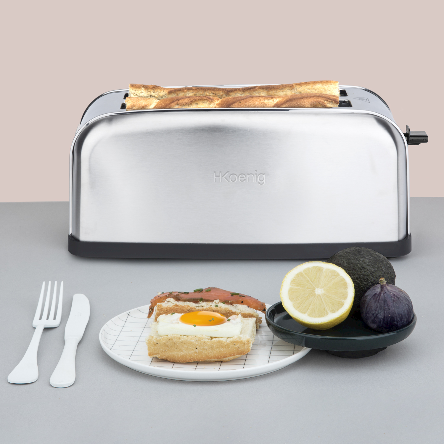 Tostapane argentato con pane, più un sandwich salmone e uovo, limone, fico e avocado.