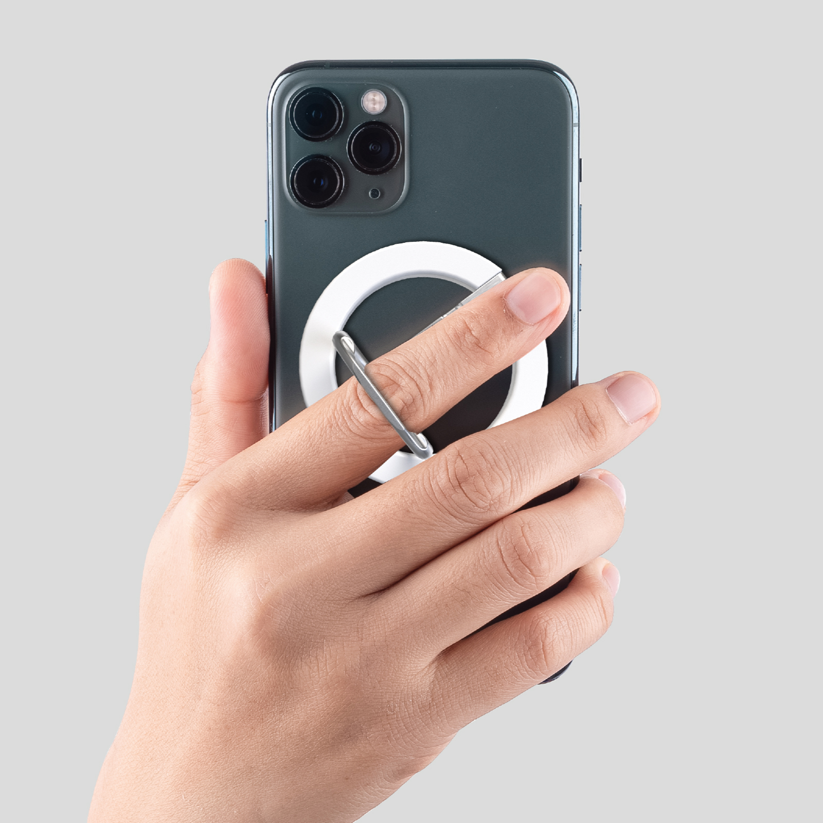 Hand hält ein dunkles Smartphone mit drei Kameras und einem weißen Ringhalter.