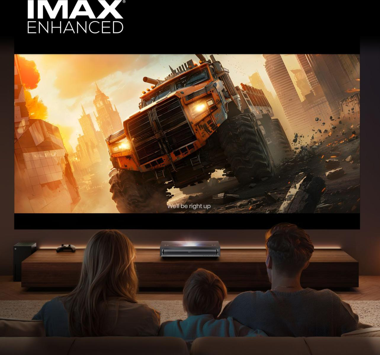 Család filmet néz IMAX vásznon: narancssárga szörnyeteg teherautó városban.