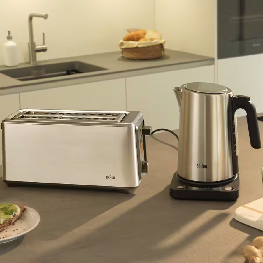Grille-pain et bouilloire en inox sur un plan de travail avec une tranche de pain grillé.