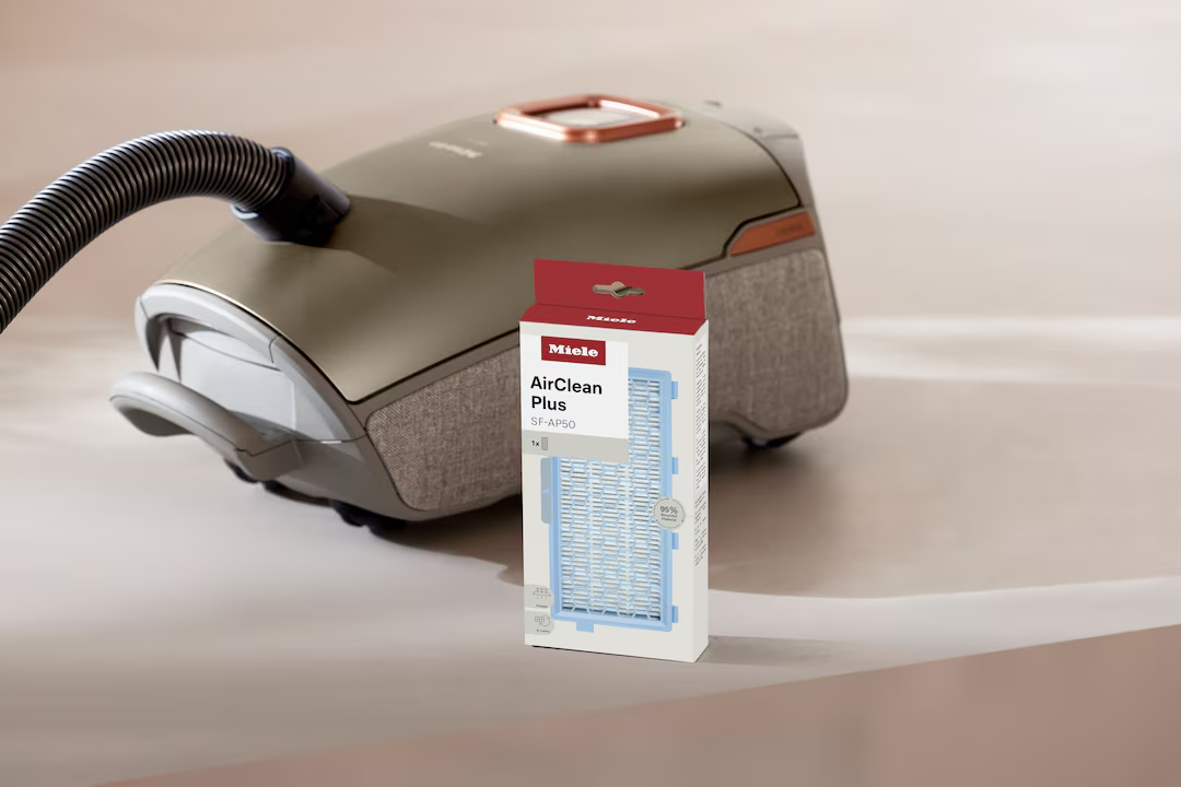 Un aspirapolvere Miele con tubo e una confezione di filtri AirClean Plus.
