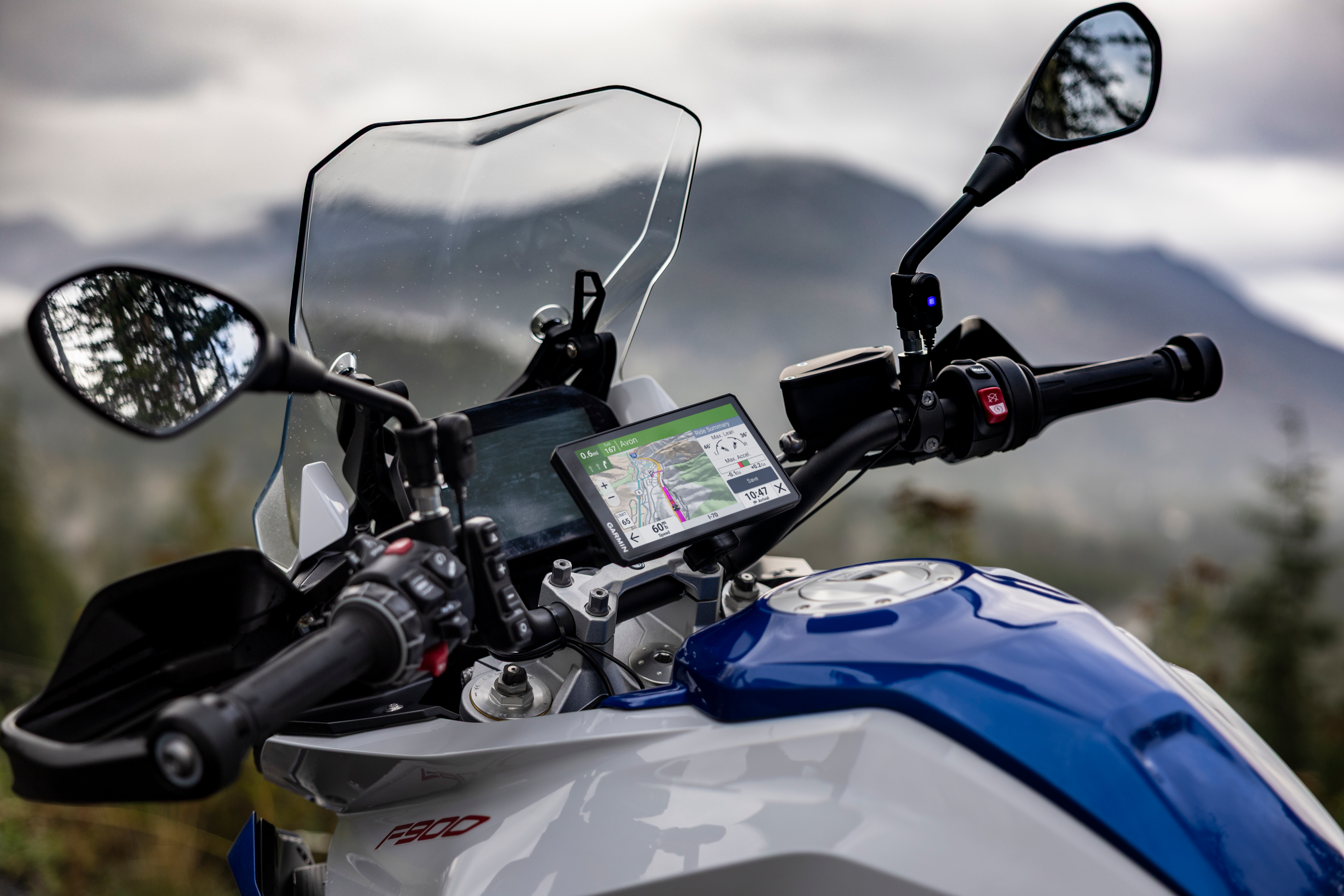 GPS moto mostra mappa; montagne sullo sfondo.