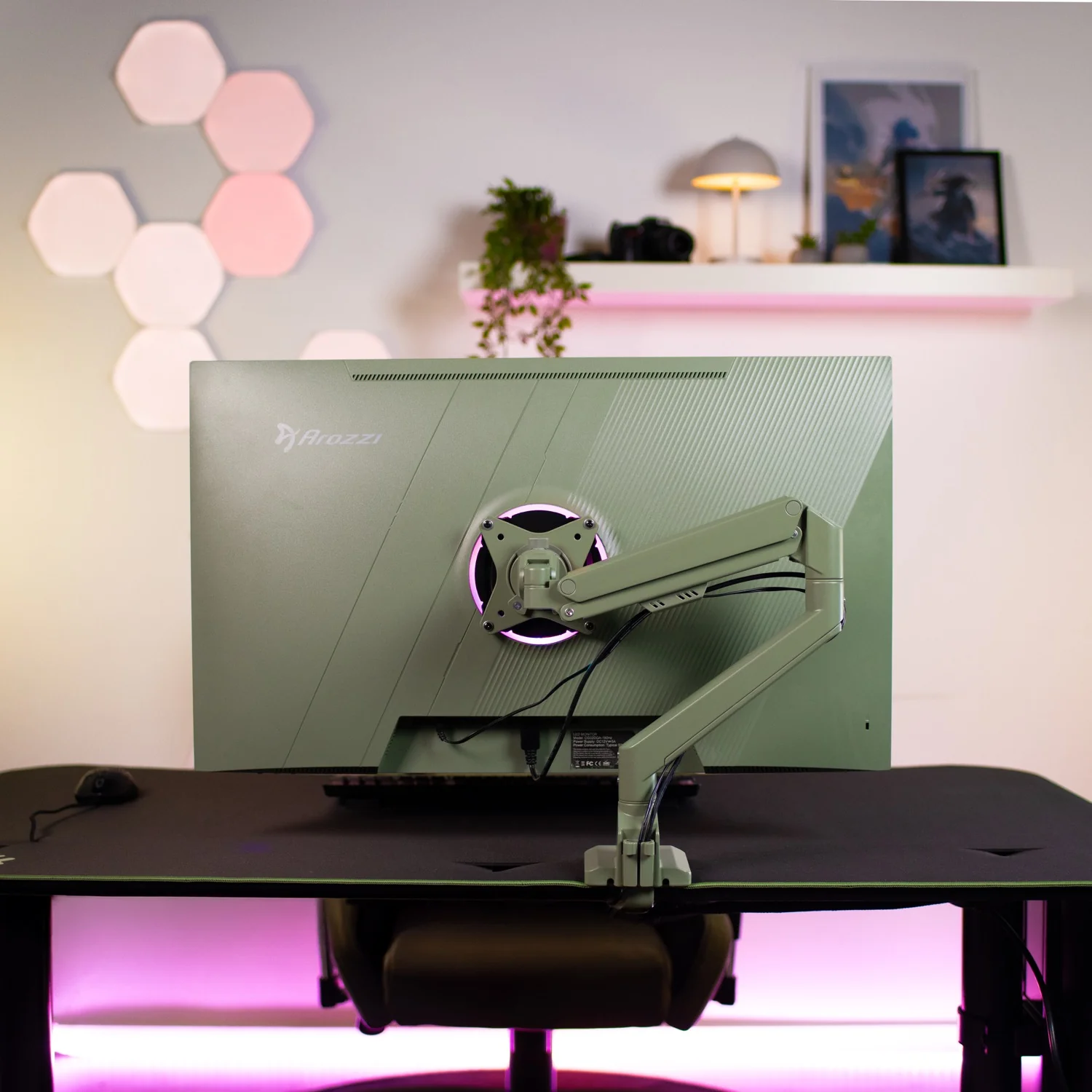 Un moniteur vert est monté sur un bureau. L'arrière-plan montre des lumières murales et des images.