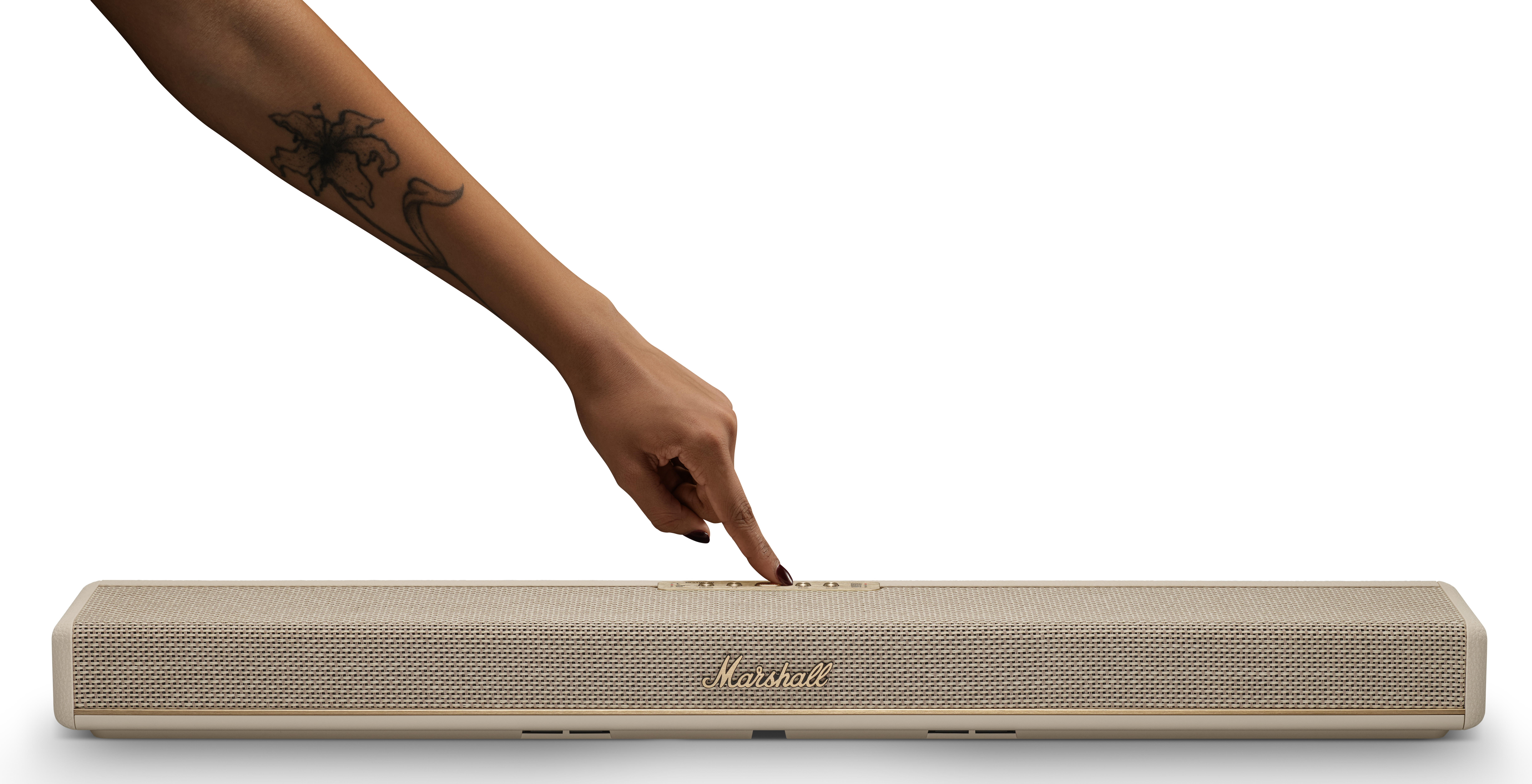 Ręka z tatuażem naciska kremowy głośnik z logo Marshall.