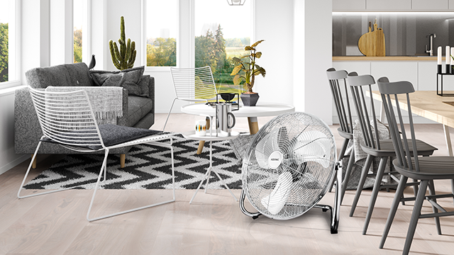 Nowoczesny salon z szarą sofą, białymi krzesłami, stołem i wentylatorem.