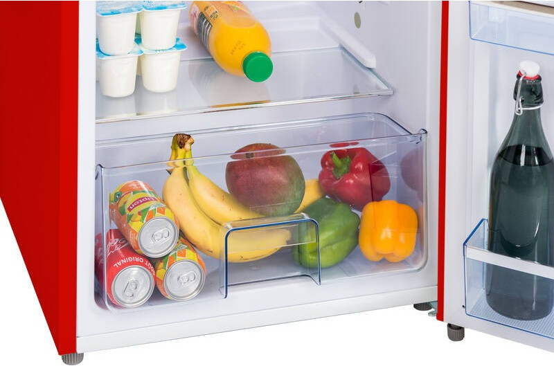 Kühlschrank mit Joghurt, Saft, Dosen, Bananen, Mango, Paprika und Flasche.