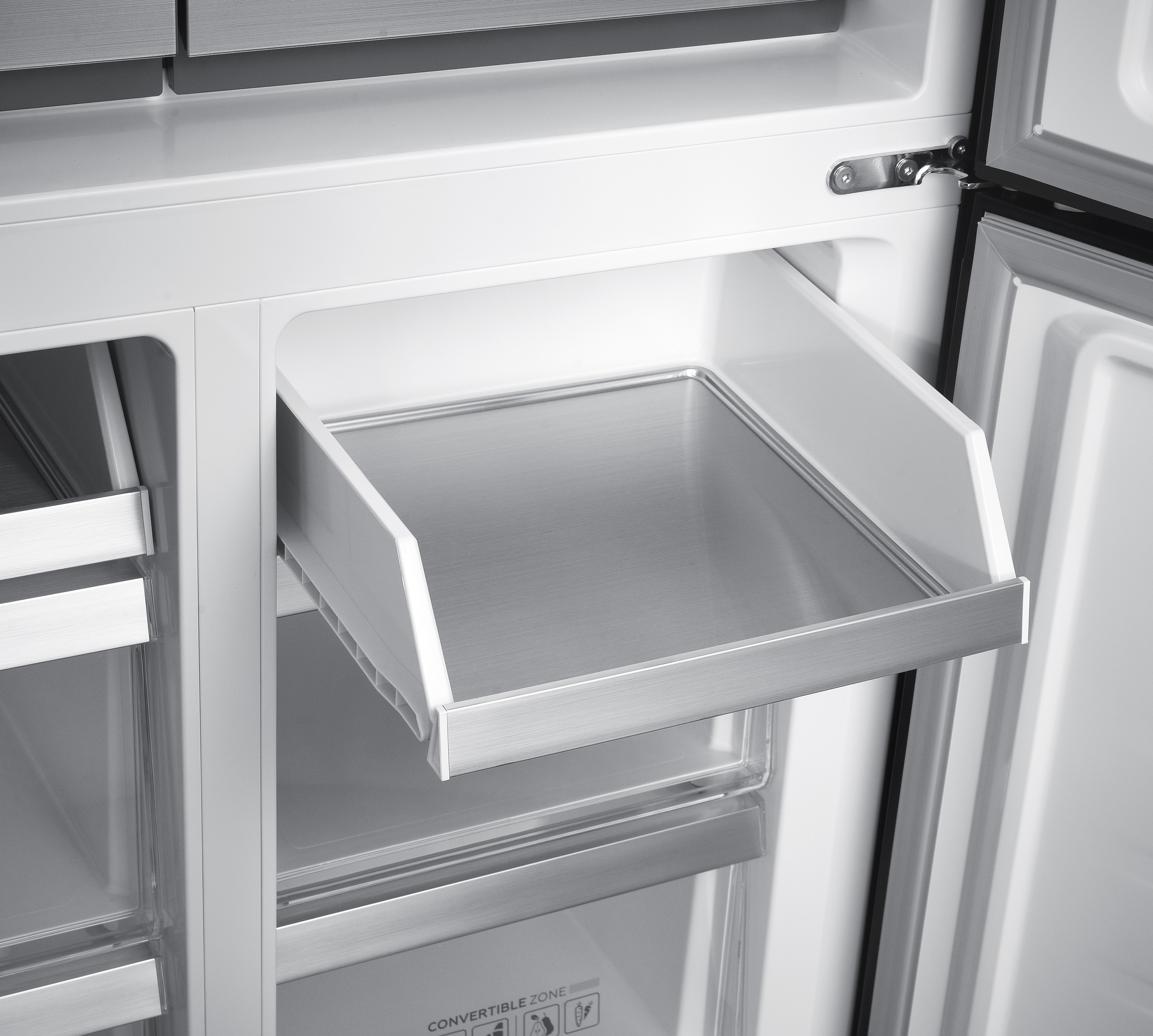 Ausgezogener Kühlschrank-Einsatz mit Metallboden und weißen Seitenwänden.
