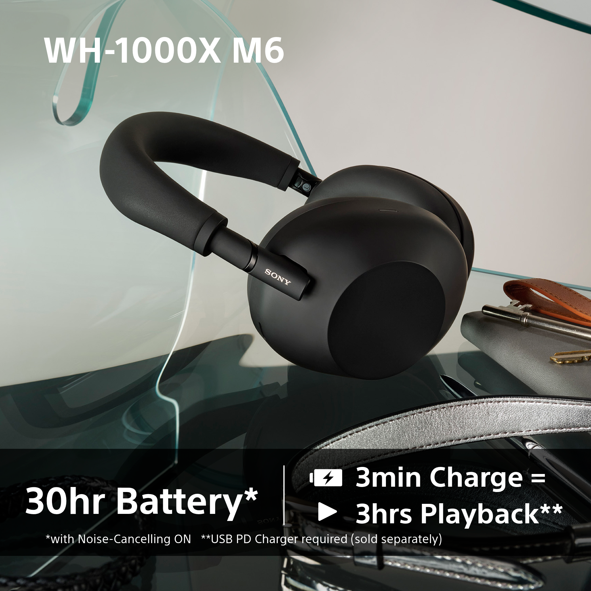 Schwarze Sony WH-1000XM6 Kopfhörer auf Glasoberfläche mit Schlüssel und Geldbörse.