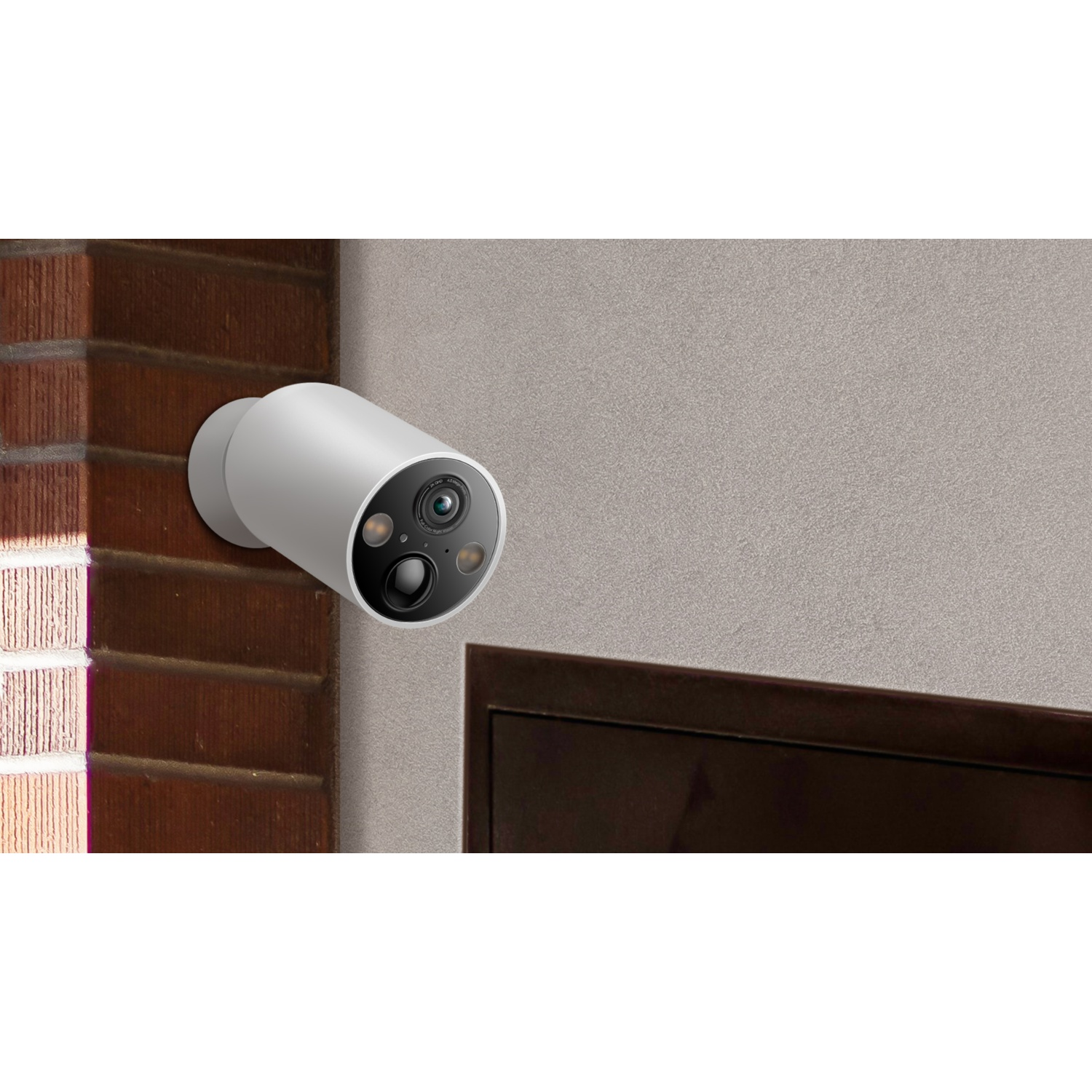 A white security camera is mounted on a brick wall.