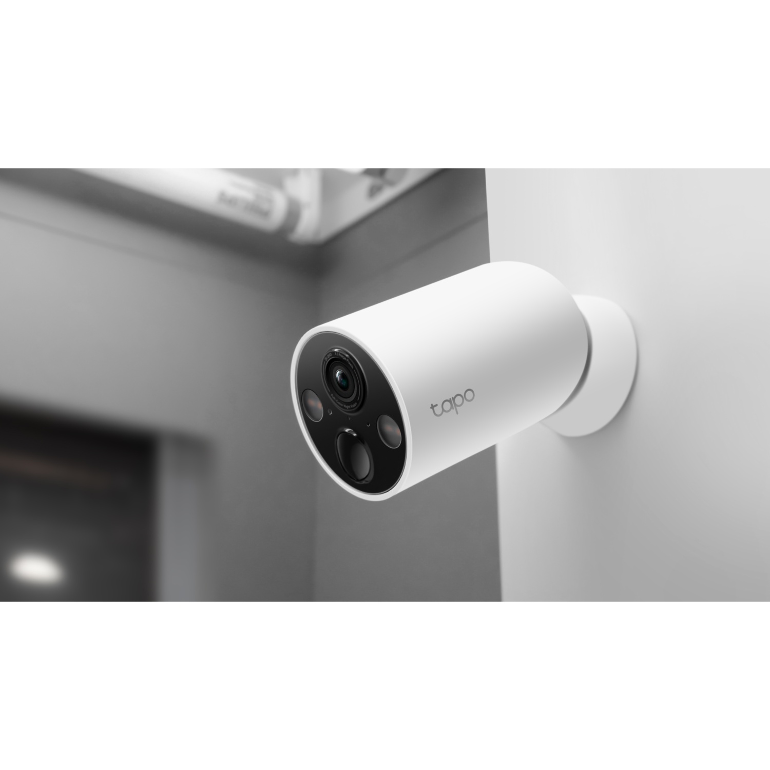 A white Tapo security camera is mounted on a wall.