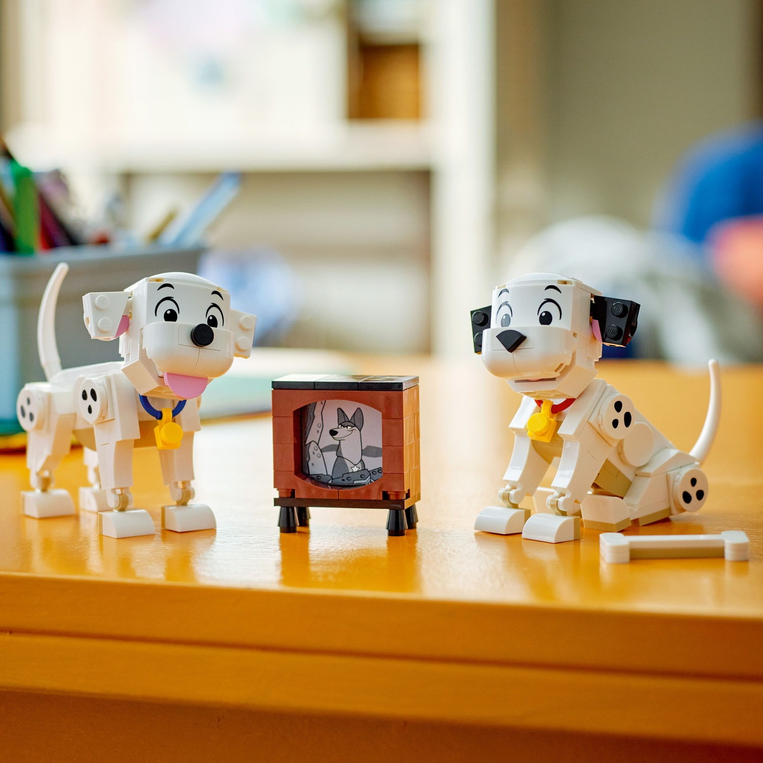 Deux chiots dalmatiens Lego assis près d'une télévision affichant une image.