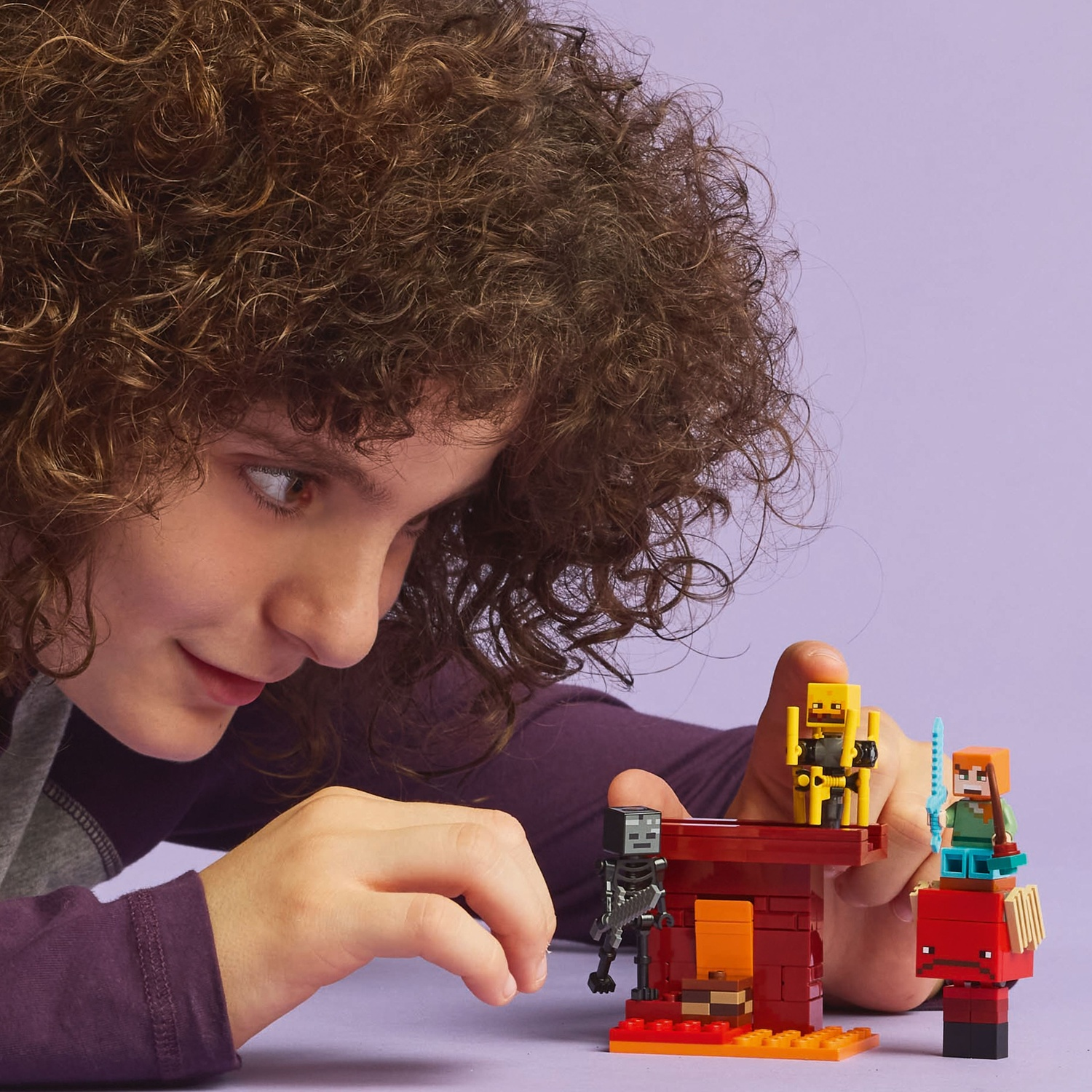 Enfant joue avec des figurines Lego Minecraft : squelette, figurine jaune et Alex.