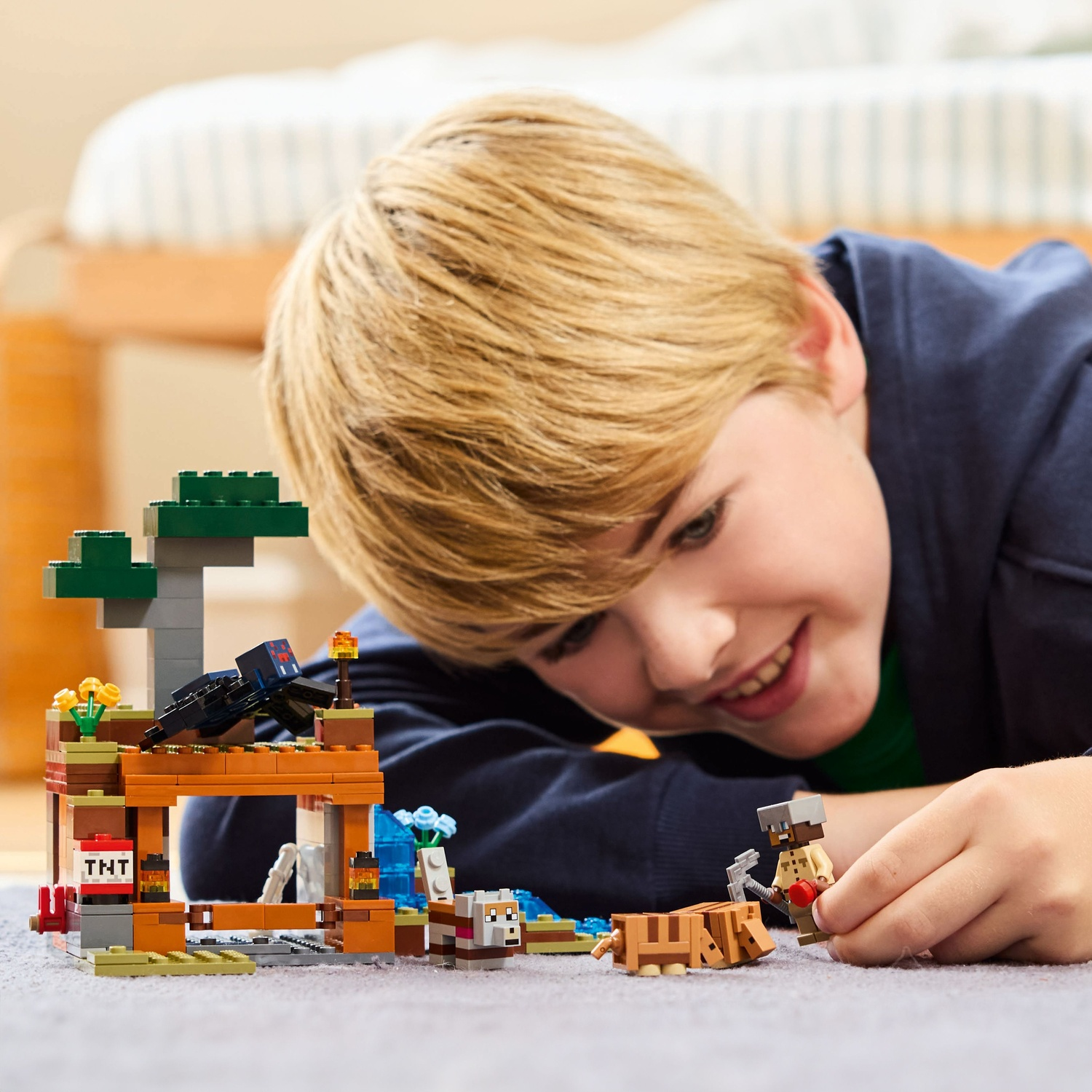 Un garçon joue avec un set Lego Minecraft représentant une mine et des personnages.