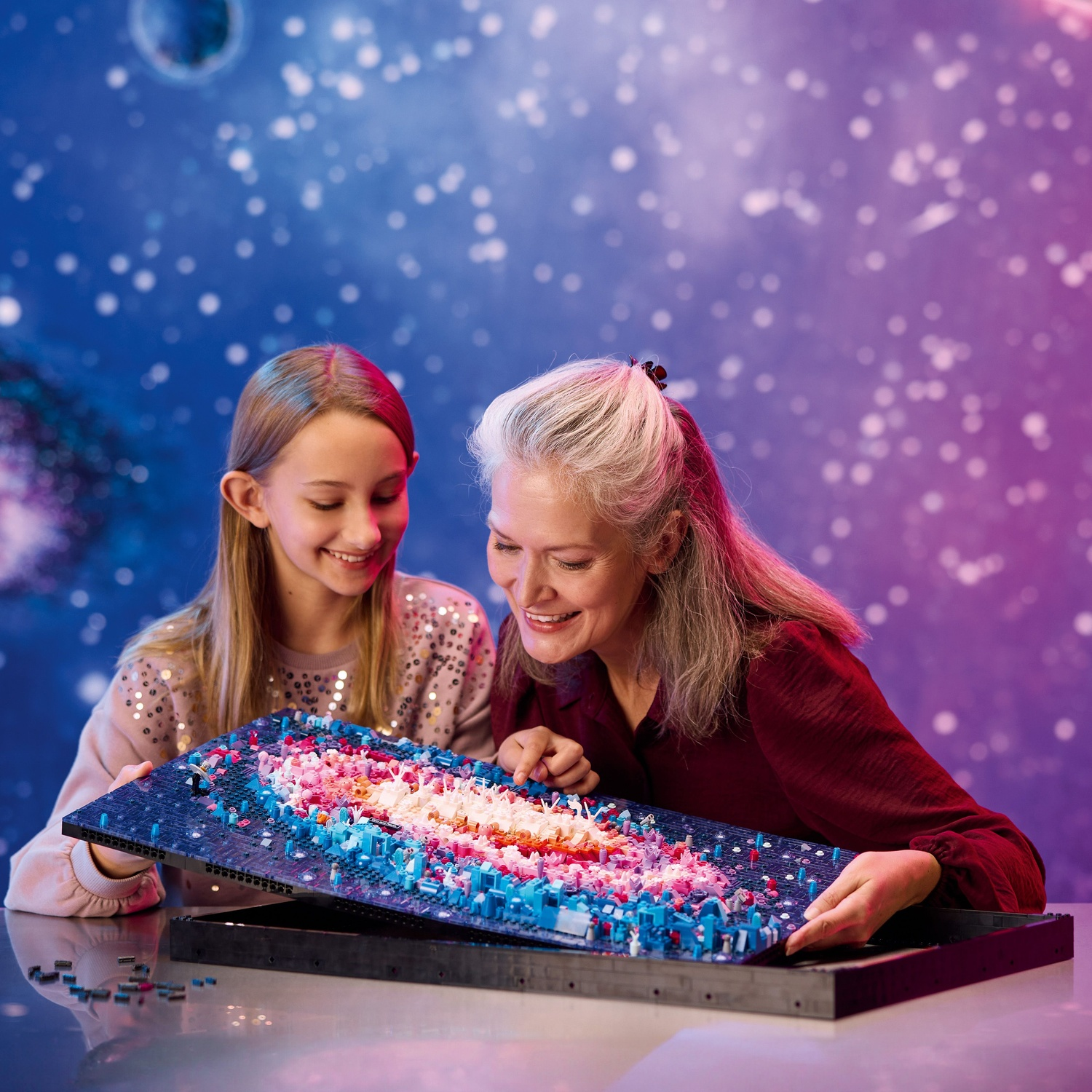 Woman and girl build a model resembling a galaxy.