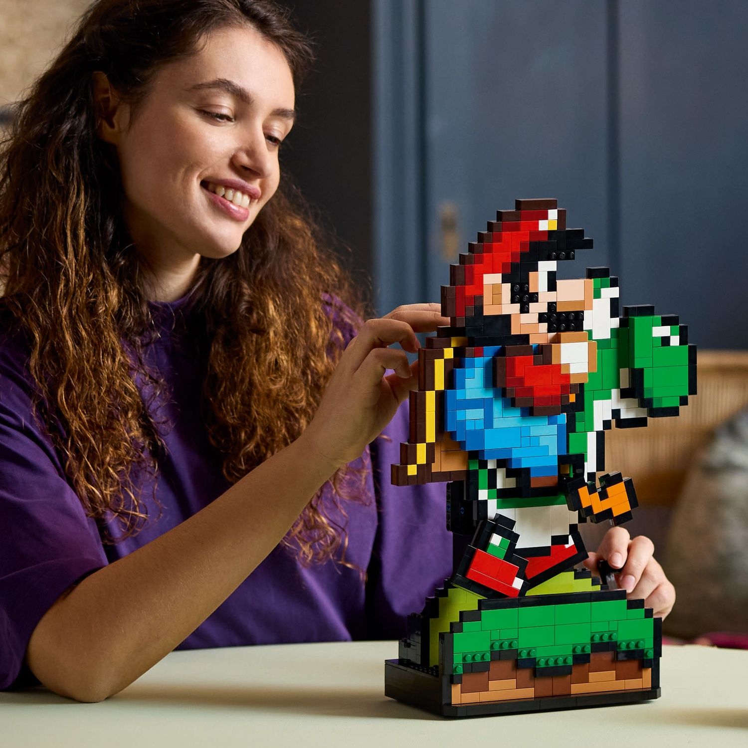Vrouw met krullend haar bouwt Mario en Yoshi van Lego-stenen.