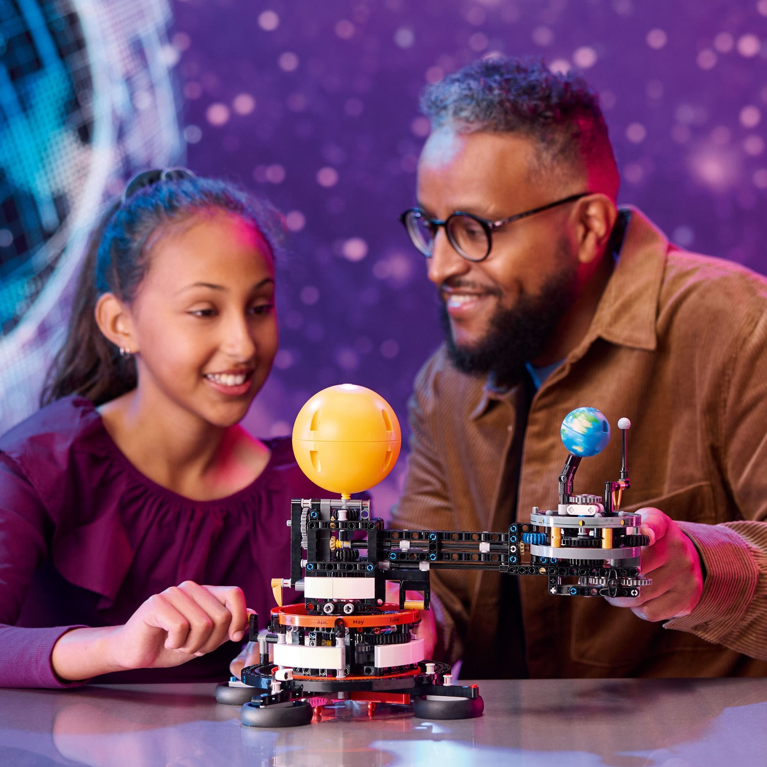 Man and girl build a solar system model with sun and Earth.