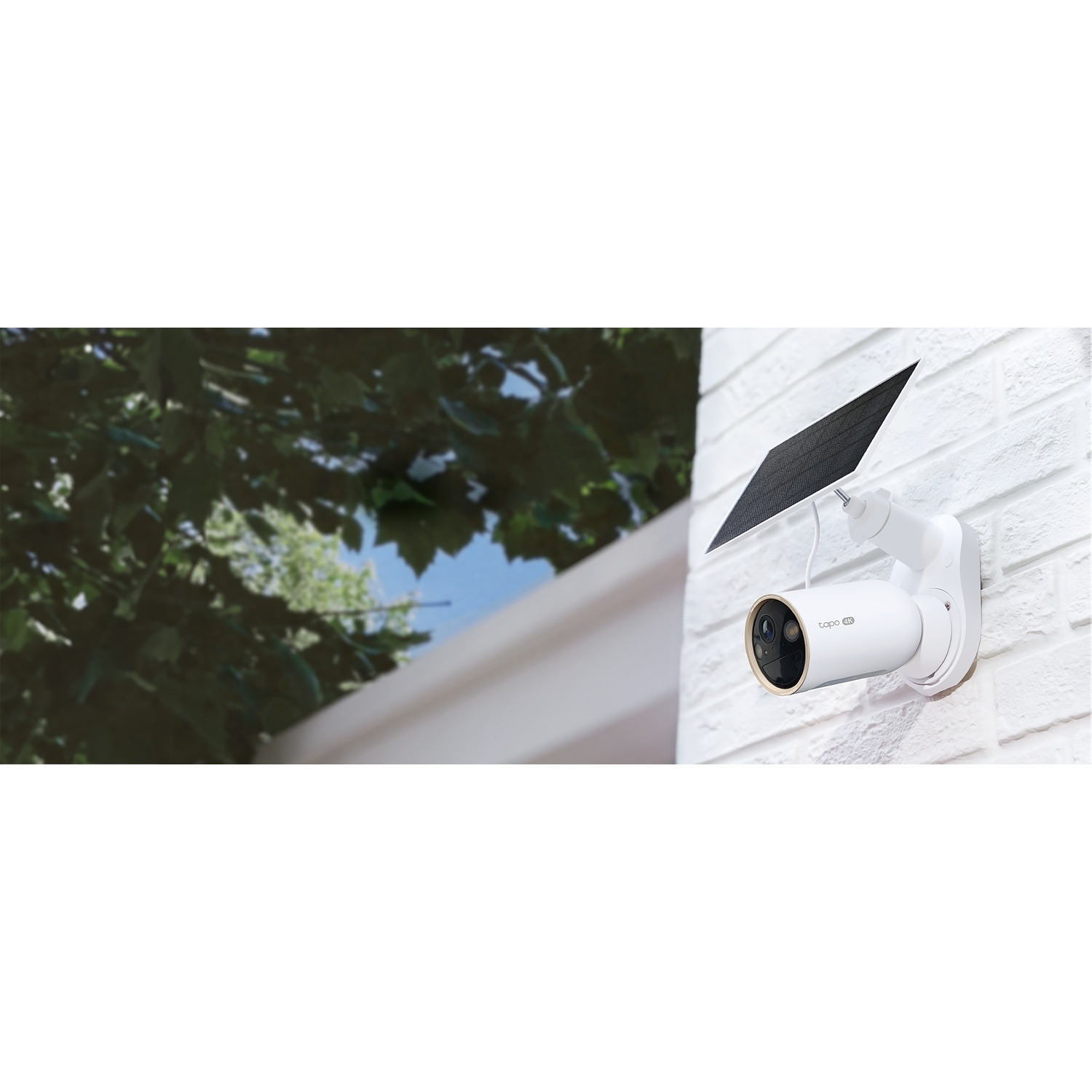 A white security camera with a solar panel mounted on a white brick wall.