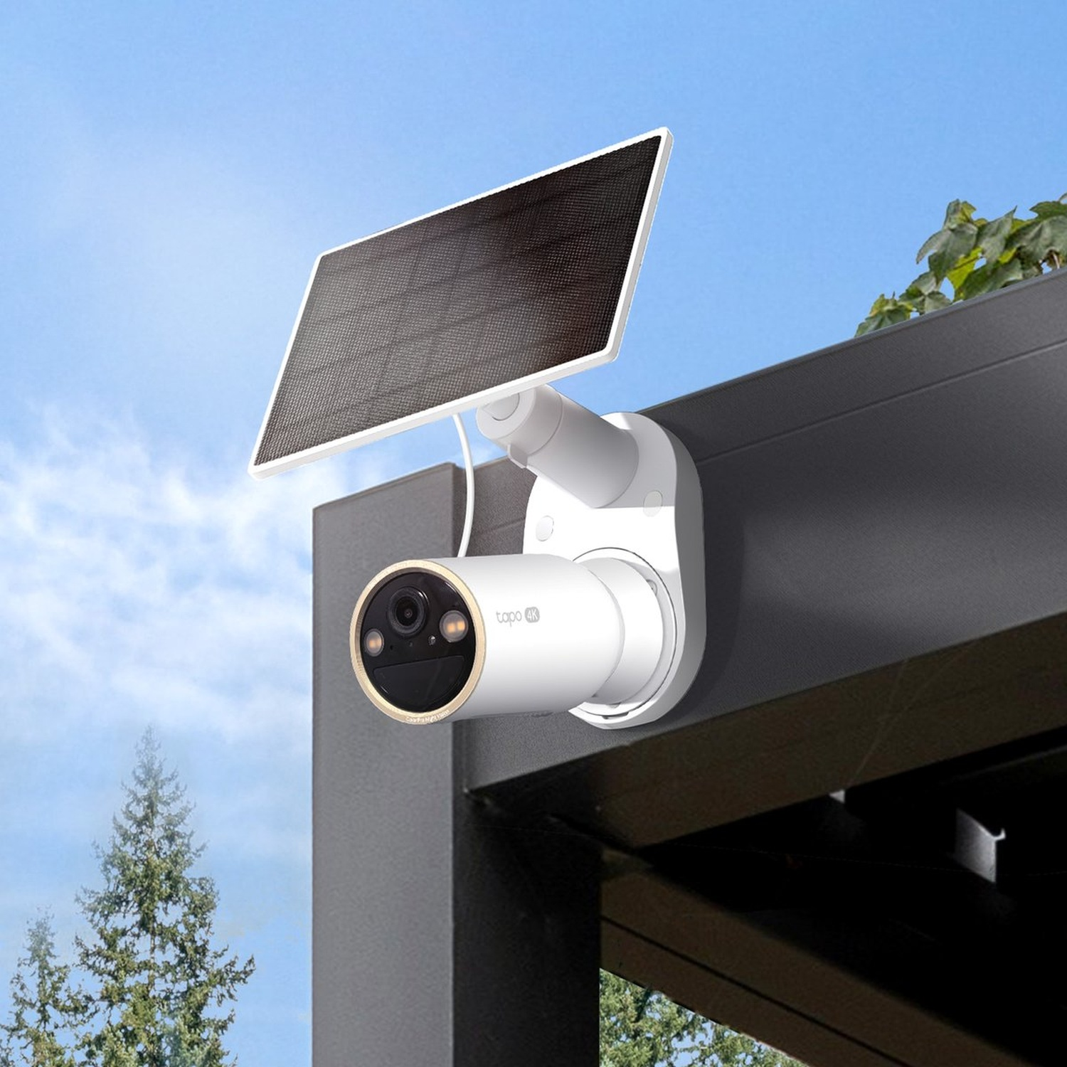 White security camera with solar panel under blue sky, trees in background.
