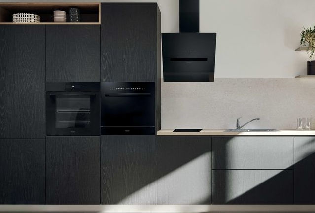 Moderne schwarze Küche mit Einbaugeräten, Spüle und Dunstabzugshaube.