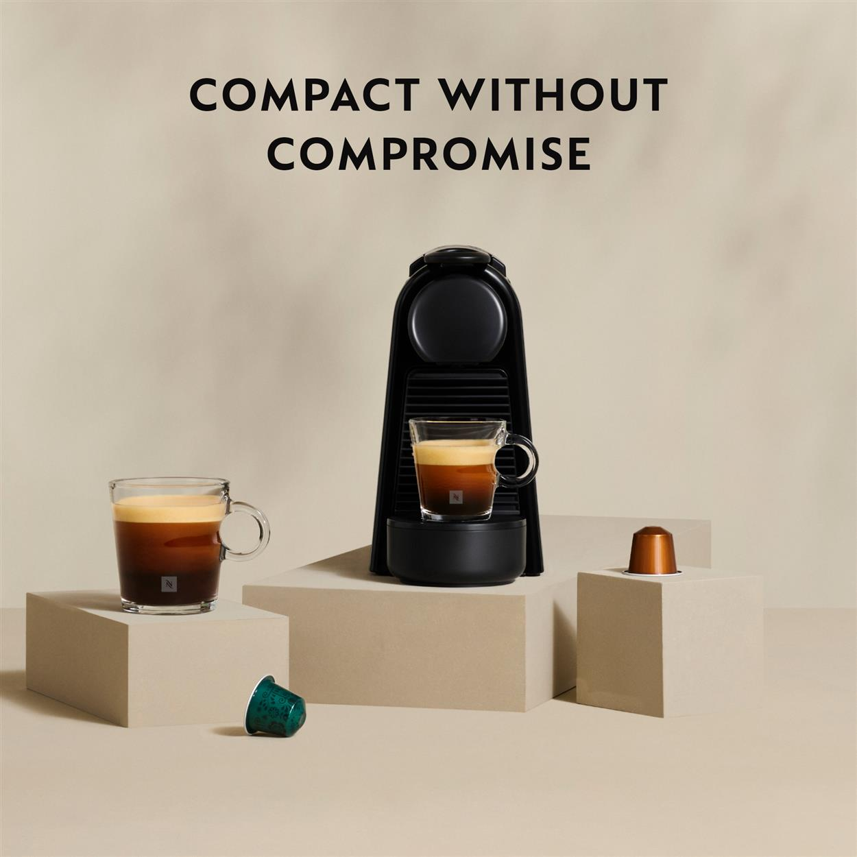 Schwarze Kaffeemaschine mit zwei Tassen Espresso und Kapseln.
