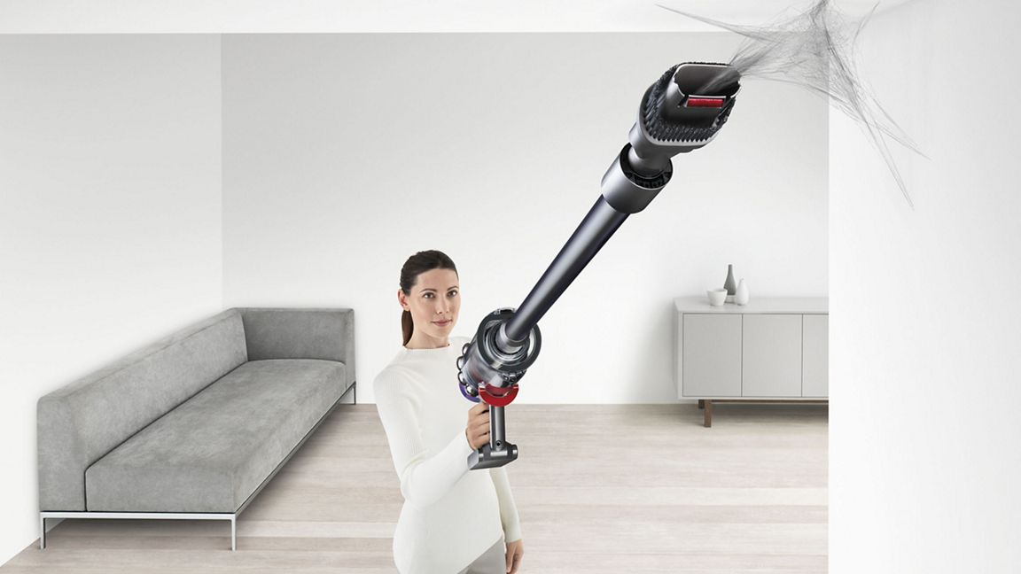 Femme aspirateur des toiles d'araignées au plafond avec Dyson.