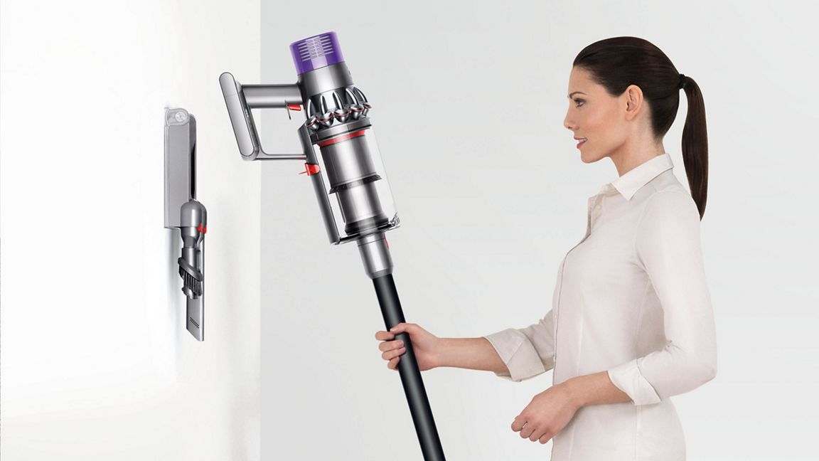 Femme avec un aspirateur Dyson fixé à un support mural.