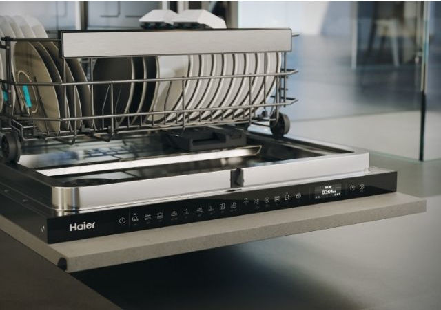 Ein offener Haier-Geschirrspüler mit beladenem Oberkorb voller Teller.