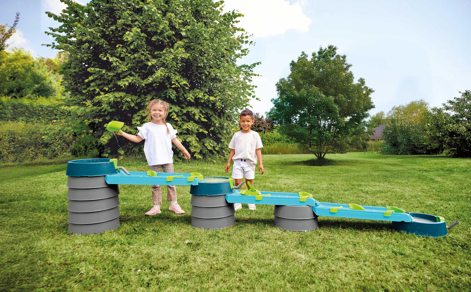 Zwei Kinder spielen im Garten an einem blauen Wasserspieltisch mit grünen Elementen.