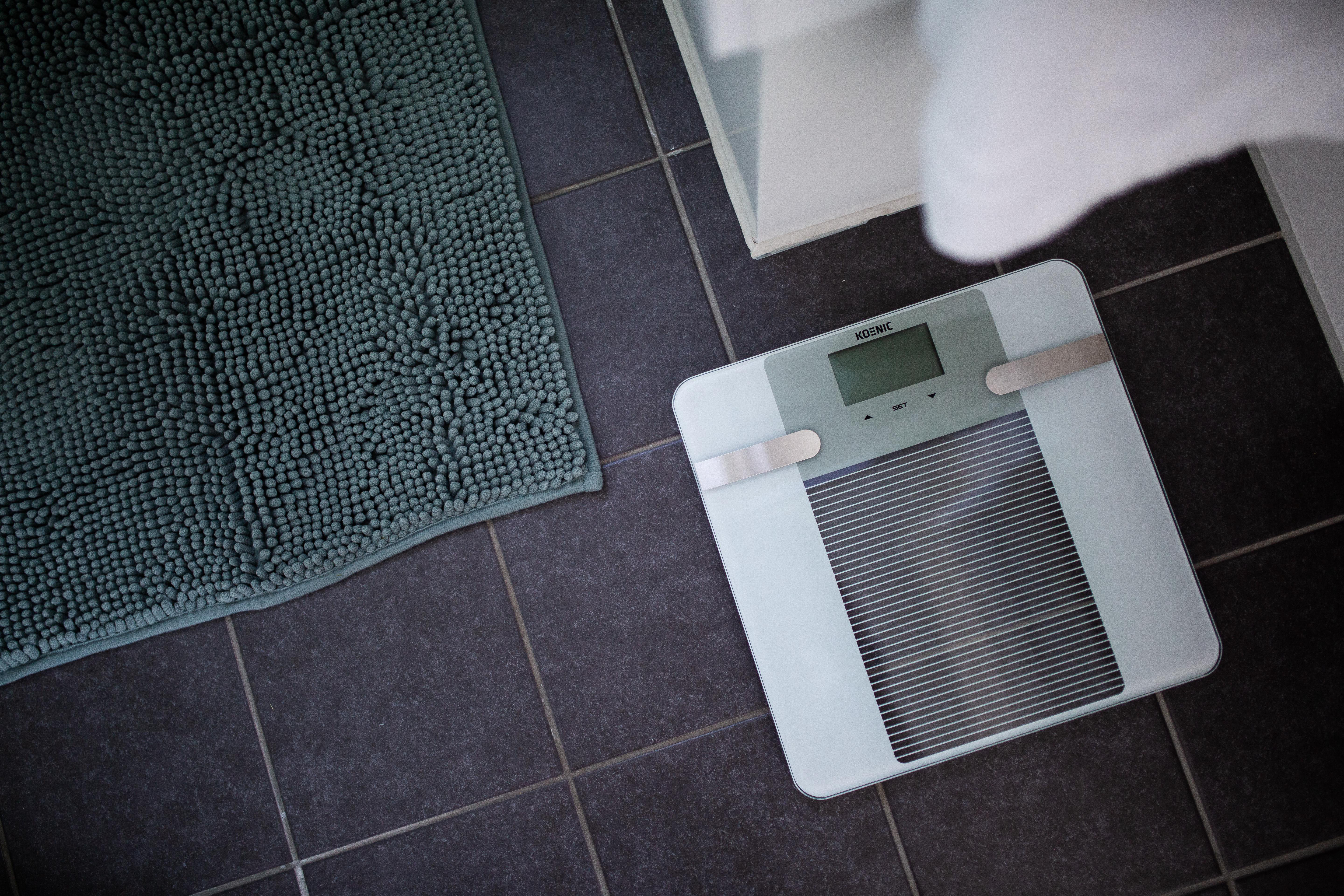 Niebieska mata i waga na ciemnych płytkach.