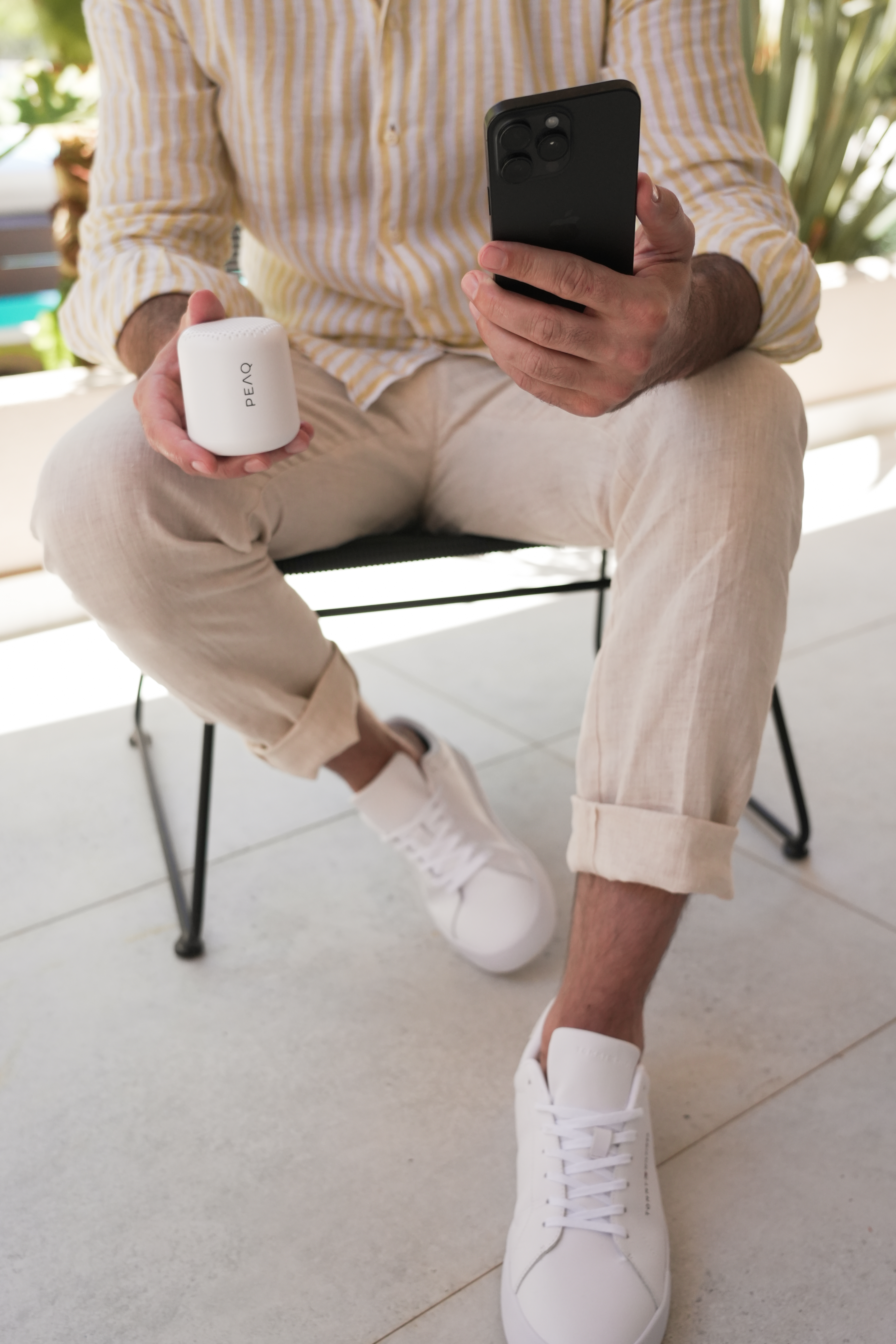 Mężczyzna w żółto-białej koszuli trzyma smartfon i głośnik.