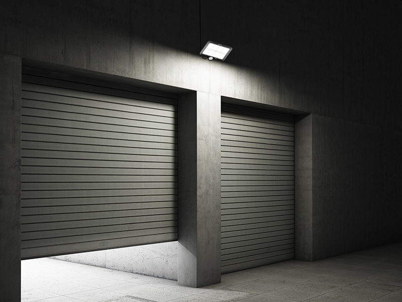 Dwoje drzwi rolowanych w betonowej przestrzeni, jedne lekko otwarte, oświetlone z góry.
