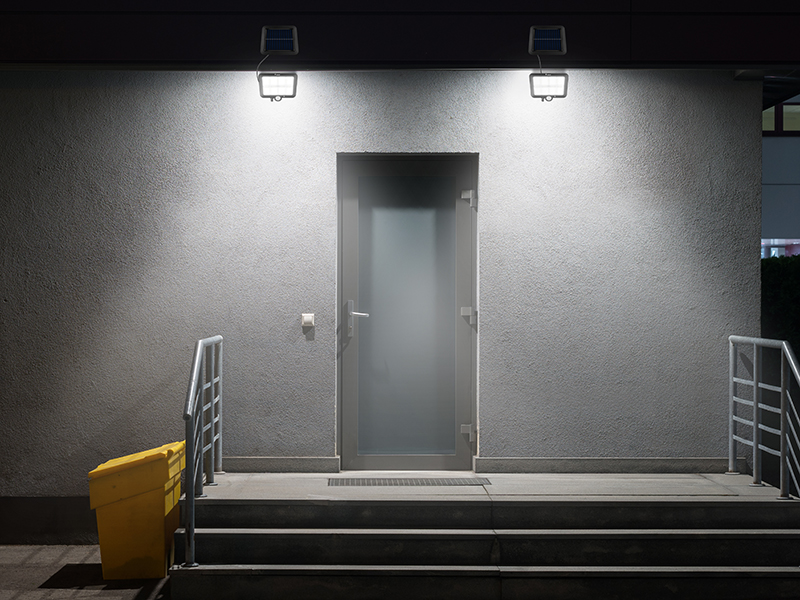 Matowe drzwi ze światłami i żółtym pudełkiem na schodach w nocy.