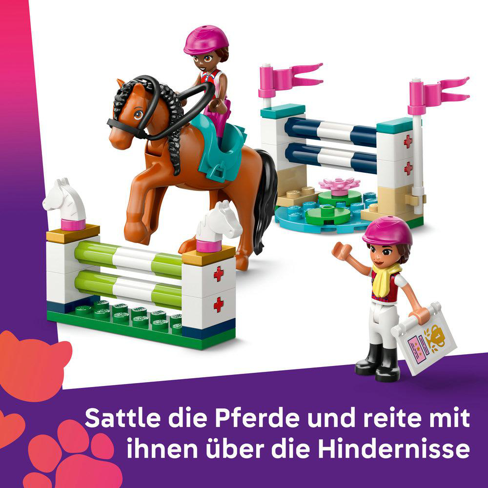 Ein Mädchen auf einem braunen Pferd reitet über Hindernisse. Ein anderes Mädchen steht daneben.