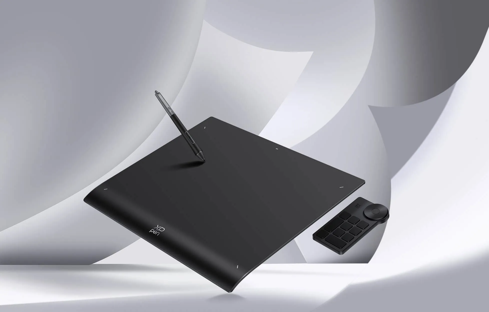 Una tavoletta grafica nera con penna e telecomando su sfondo bianco.