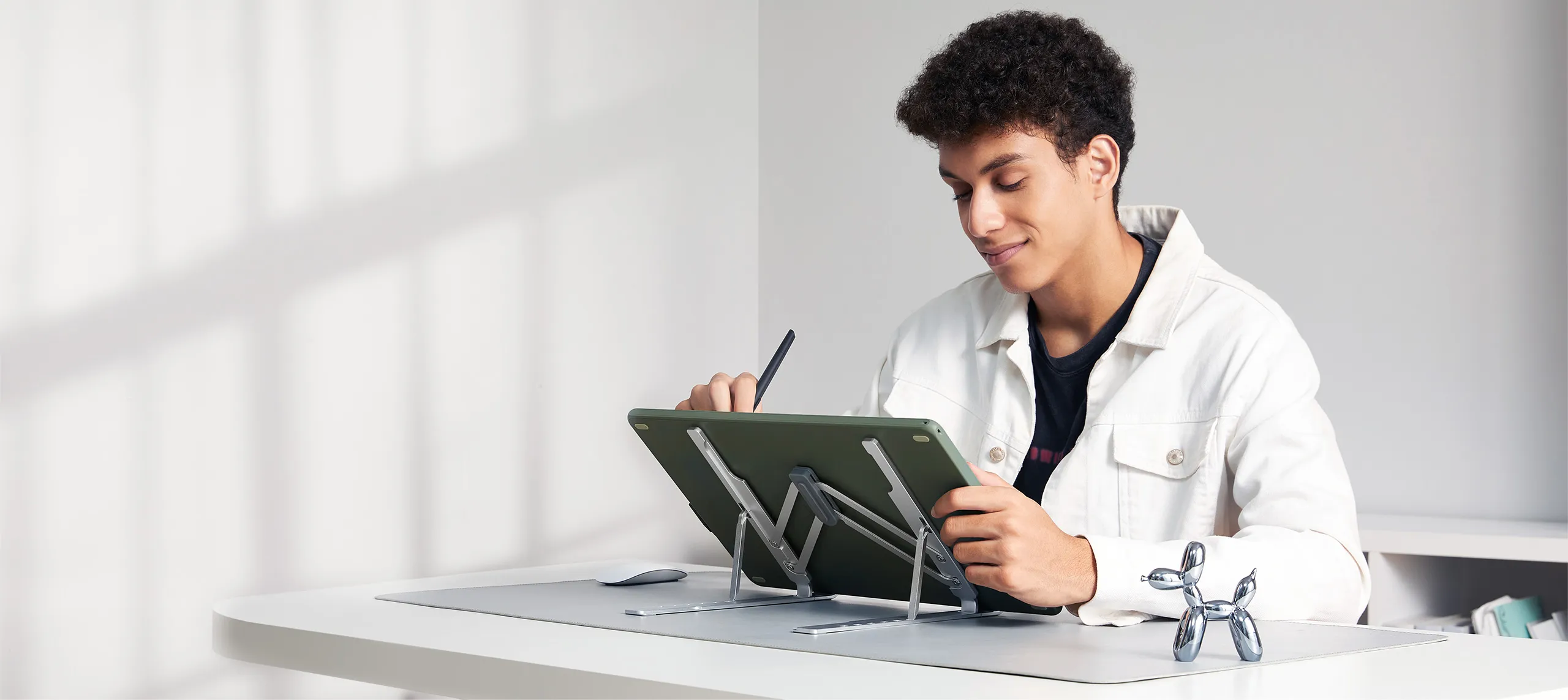 Un uomo è seduto a una scrivania, disegna su un tablet con uno stilo.